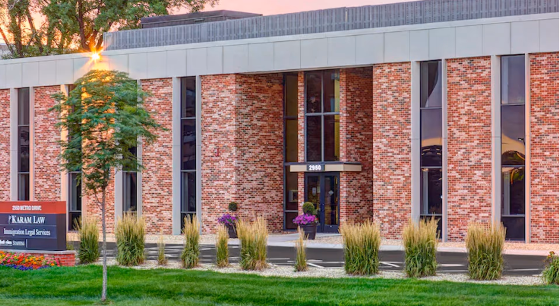 Exterior view of a brick facility entrance with glass doors and landscaping.