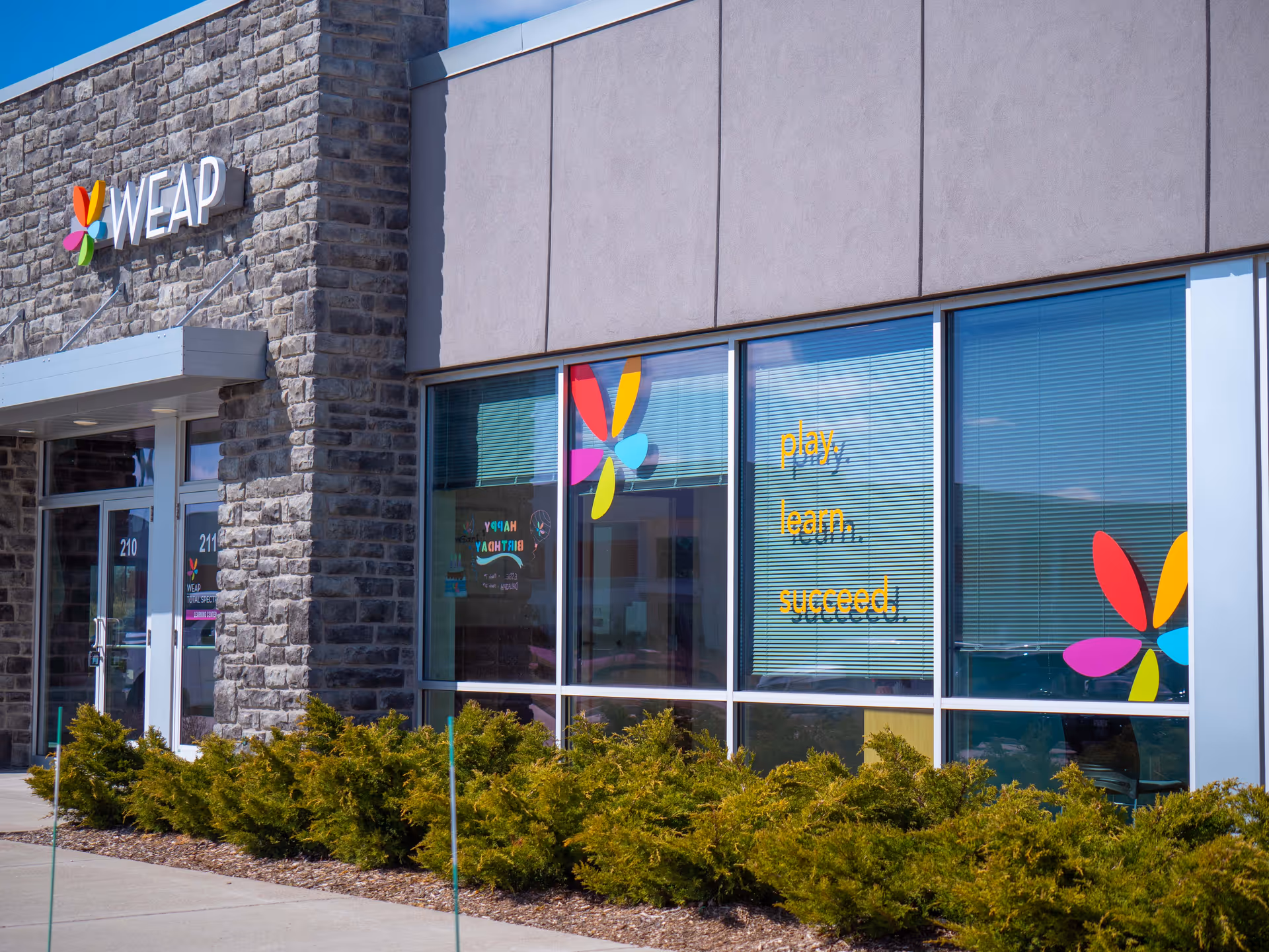 Exterior view of a modern building with large windows and colorful logos