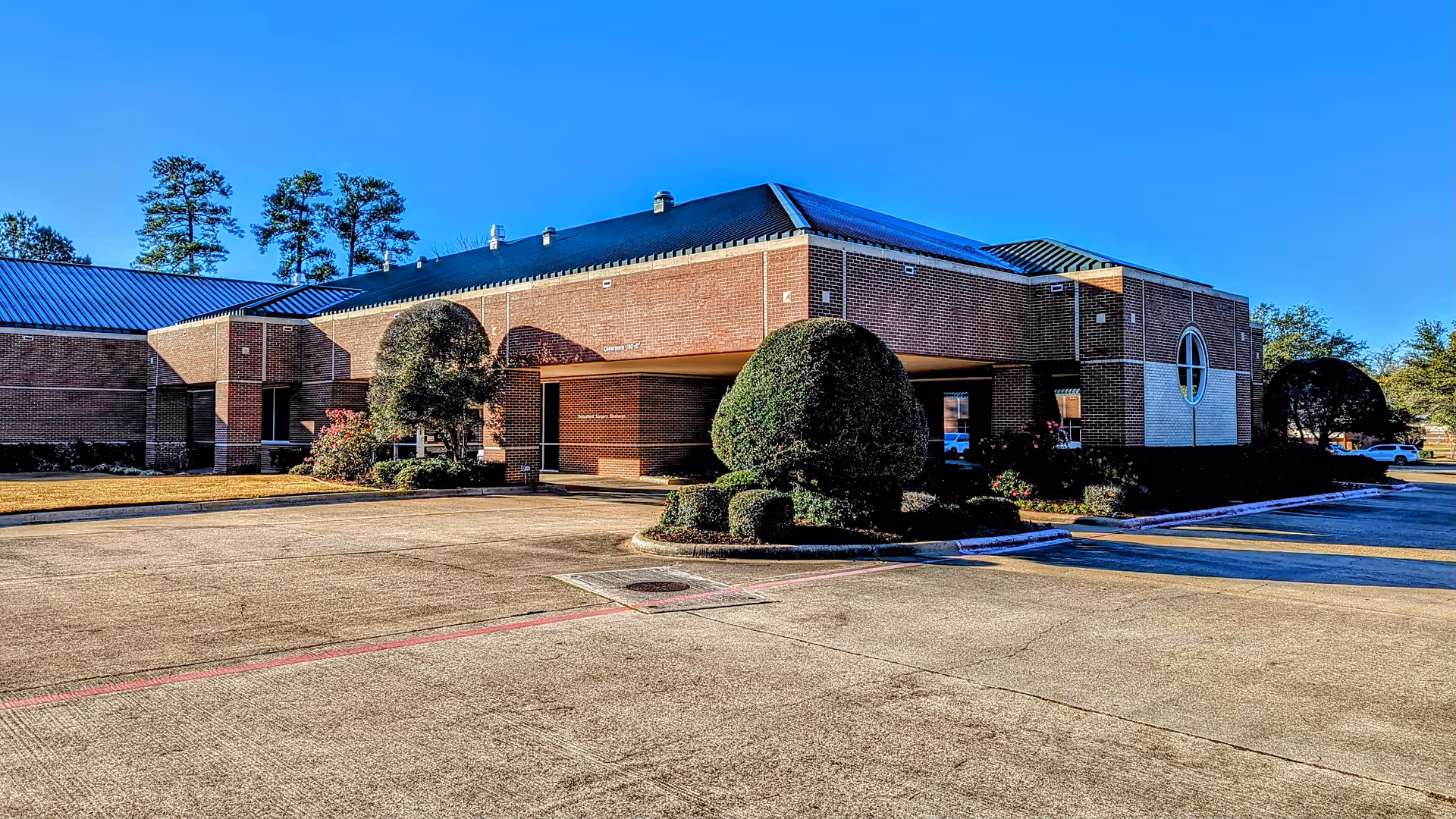 Exterior view of Texarkana Surgery Center with brick facade, entrance, and surrounding parking.