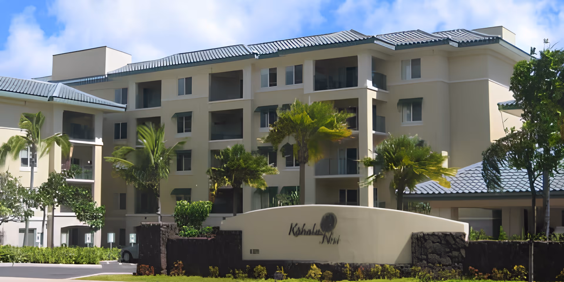 Front exterior of the Kāhala Nui senior living building with a curved entrance sign, palm trees, and multi-story balconies.