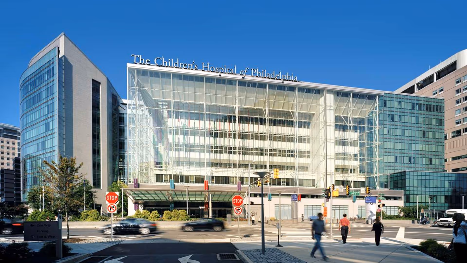 Glass-front hospital building with The Children's Hospital of Philadelphia sign and pedestrians.