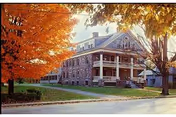 Exterior view of Holton Memorial Home: brick building with porch and autumn trees.