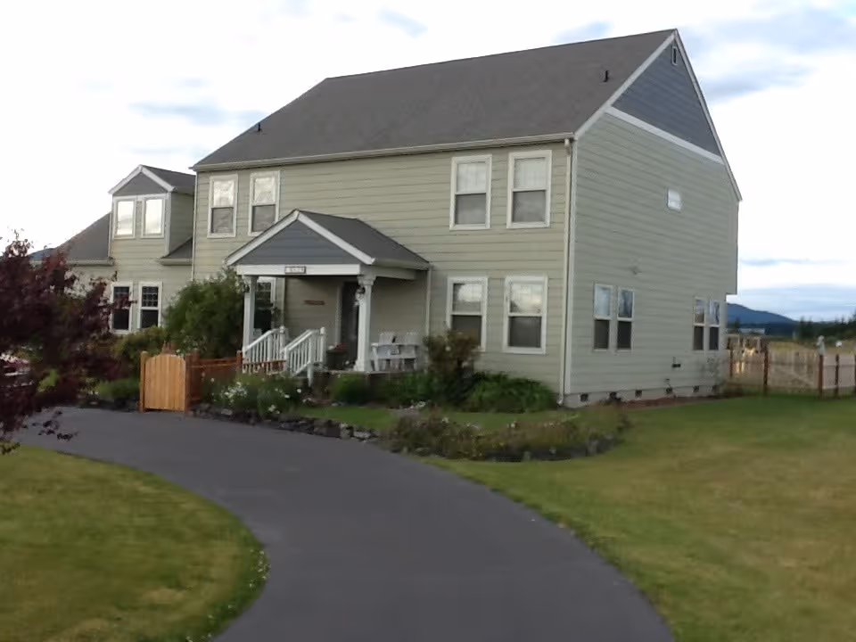 A two-story beige residential-style home with a curved driveway and small front porch.