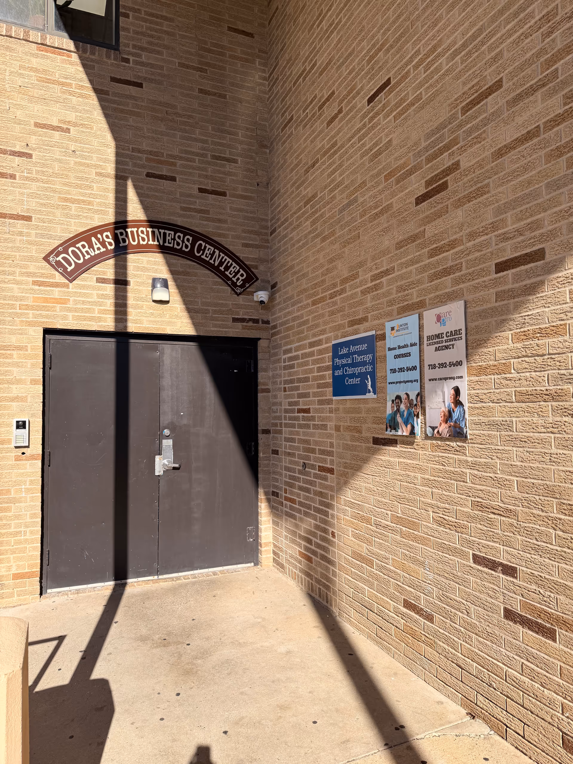 Brick exterior with a metal double door and informational signs at the building entrance.