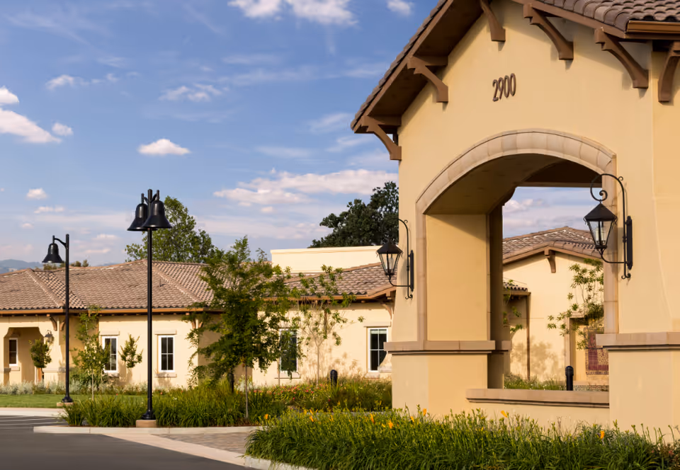 Exterior view of Creekview Health Center entrance with arch, landscaping, and blue sky.