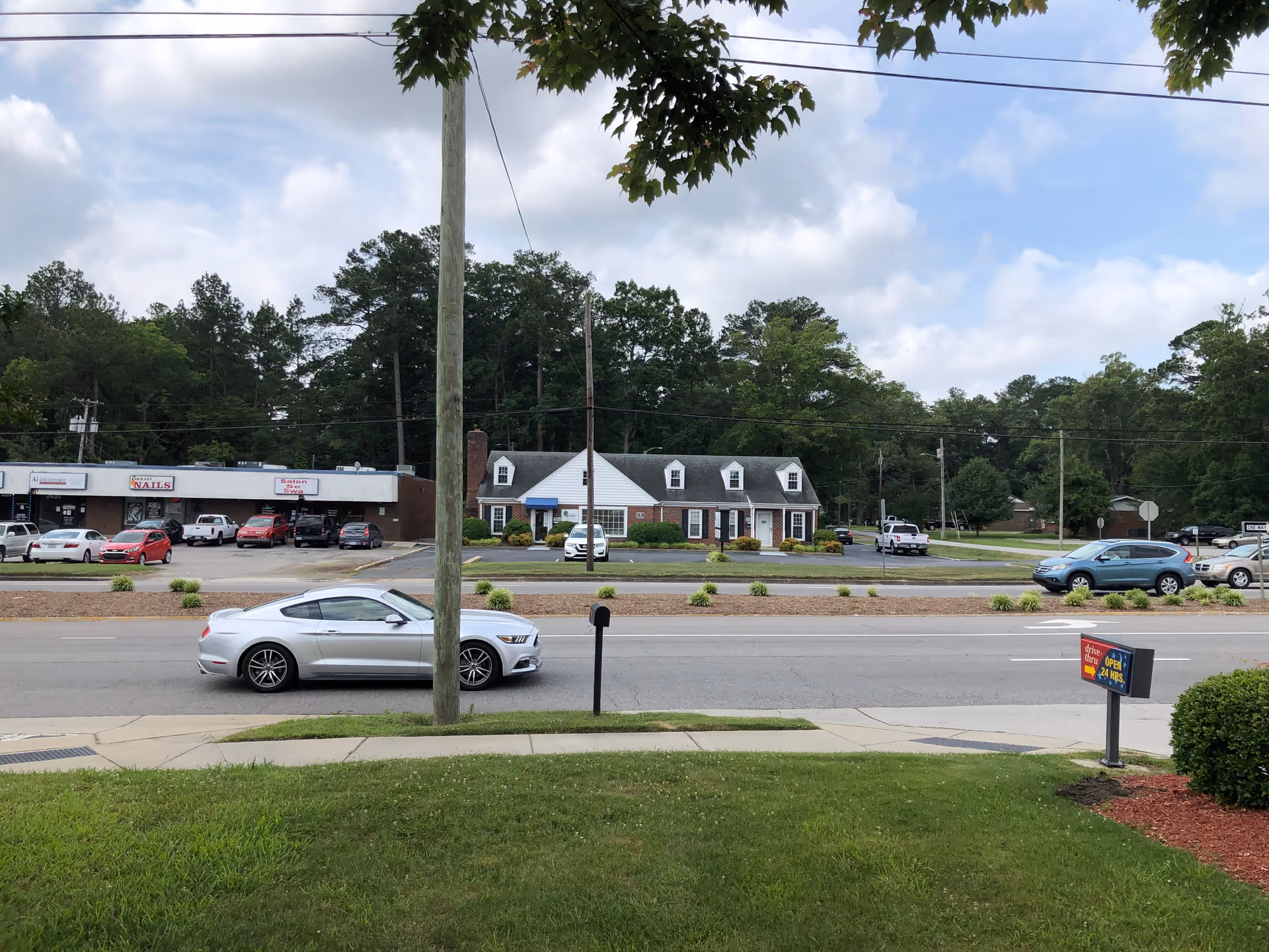 Exterior street view shows storefronts, townhouses, cars, and a grassy sidewalk.