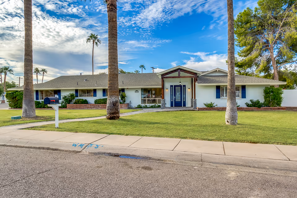 Front exterior view of Vista Living Camelback, a single-story senior facility with palm trees.