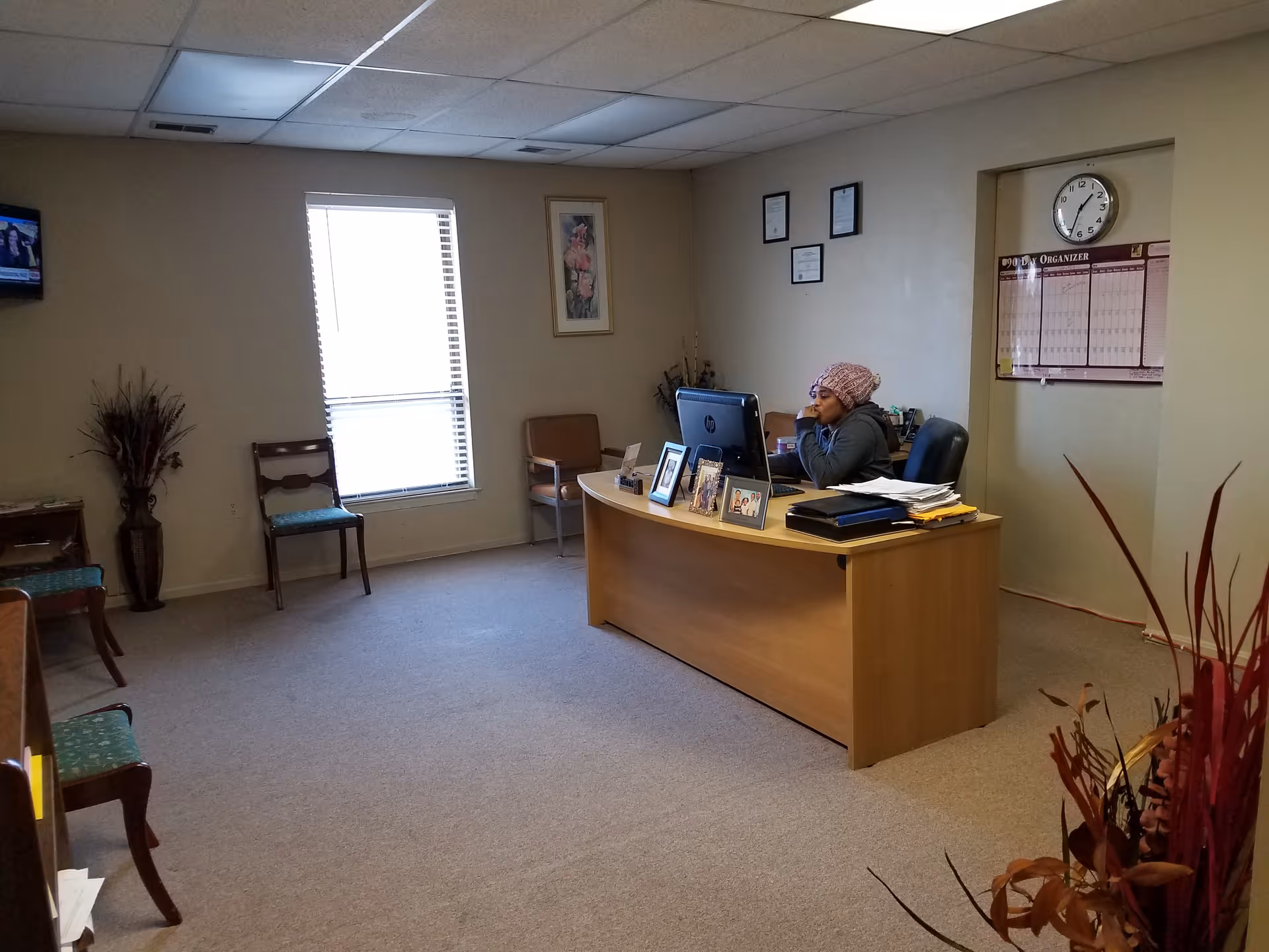 Reception area with staff at a desk and computer in a small office.