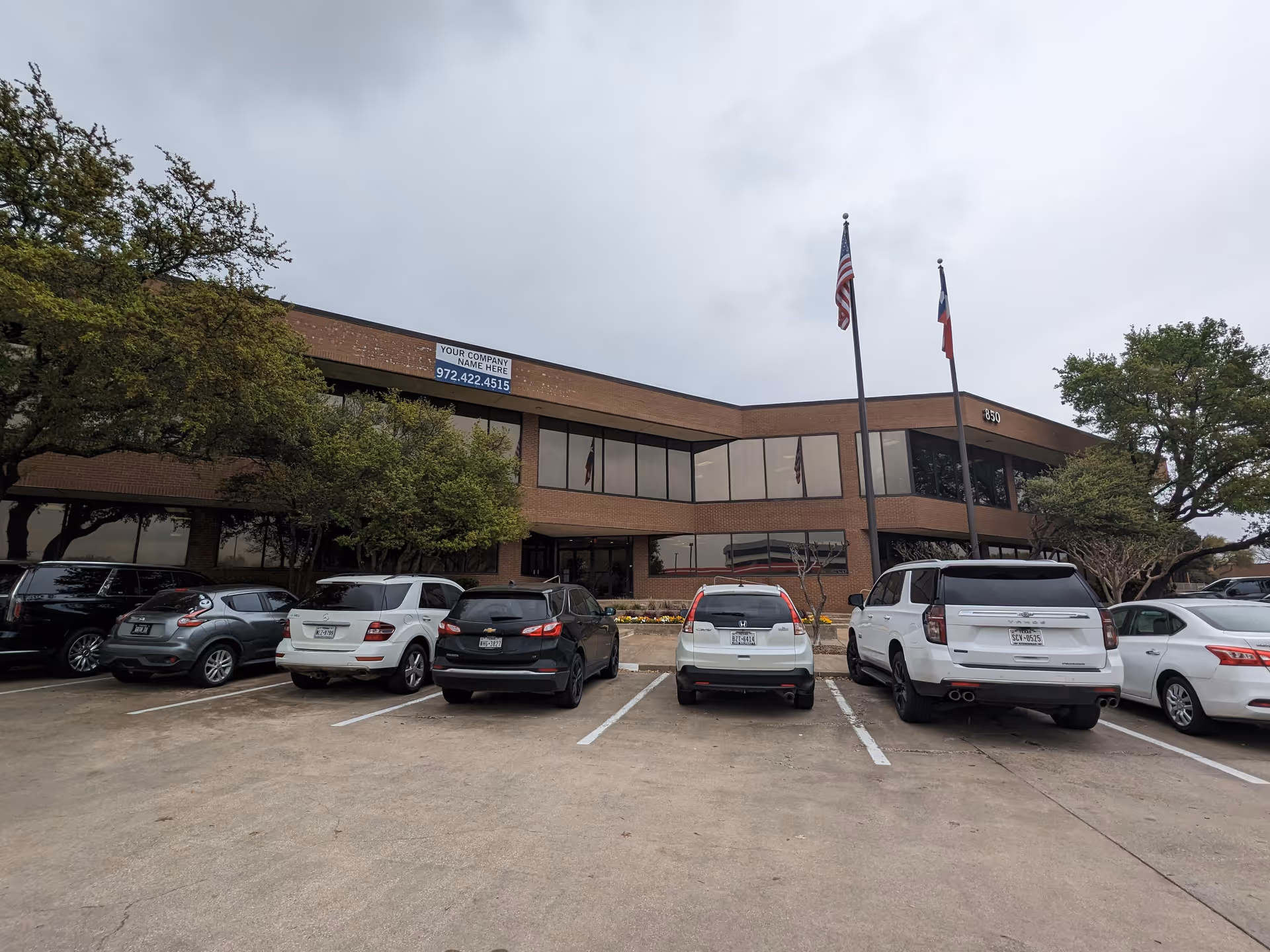 Two-story brick senior care facility with a front parking lot and flags.