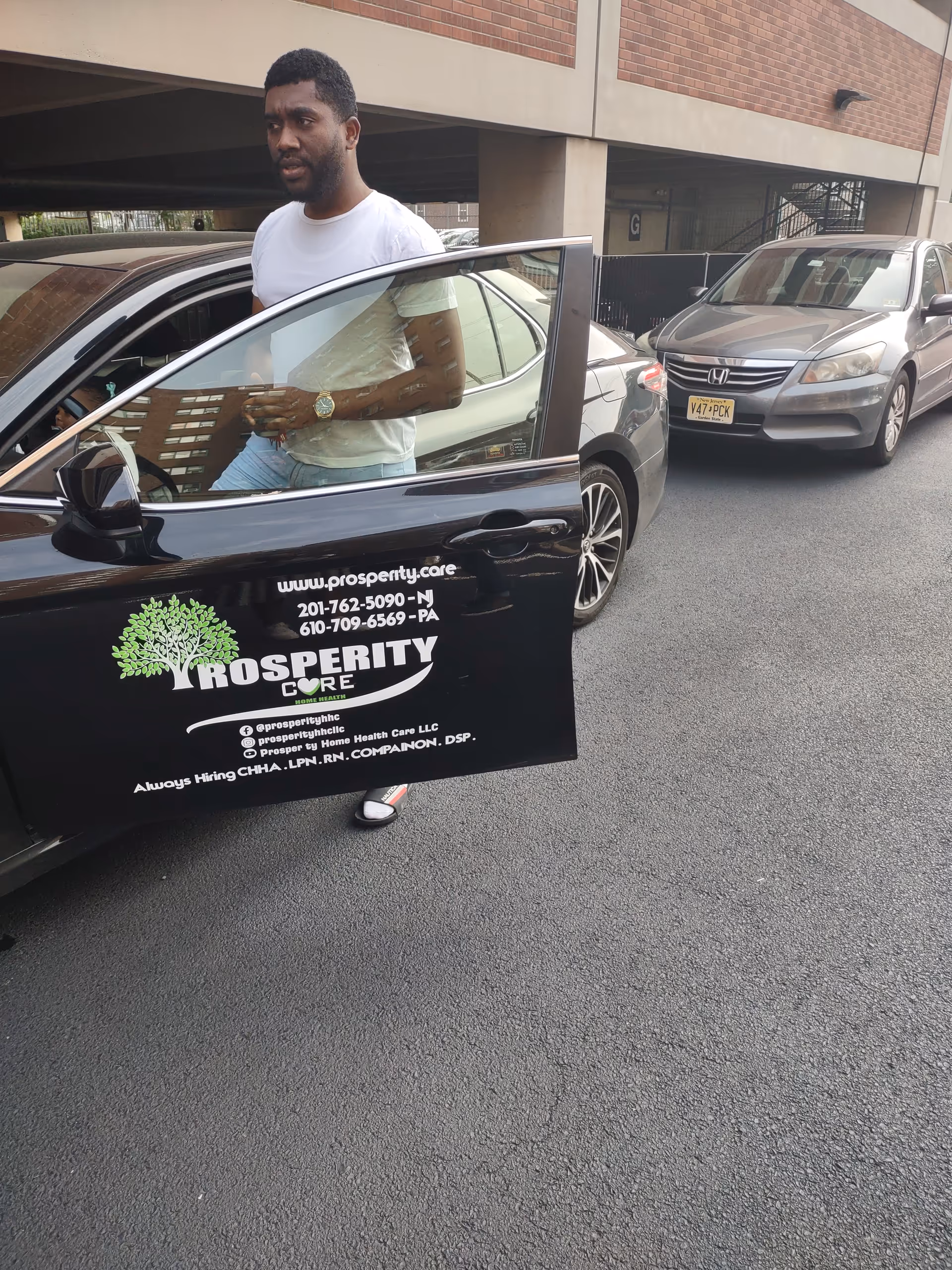A man exits a car from a Prosperity Home Health Care vehicle in a parking lot.