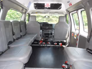 Interior of a grey passenger van with multiple seats and tie-down straps