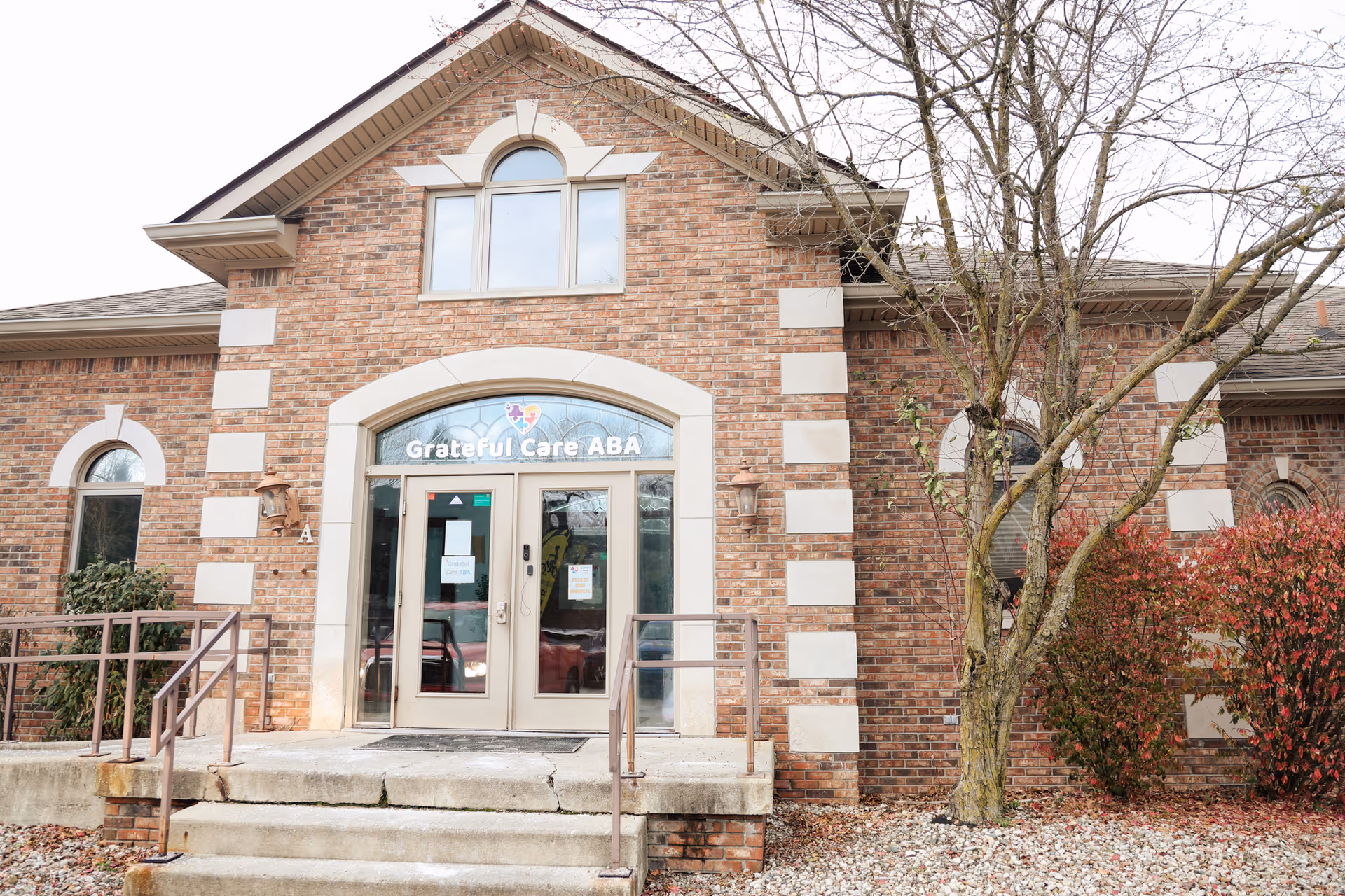 Brick facility entrance with arched glass doors and Grateful Care ABA Therapy signage.