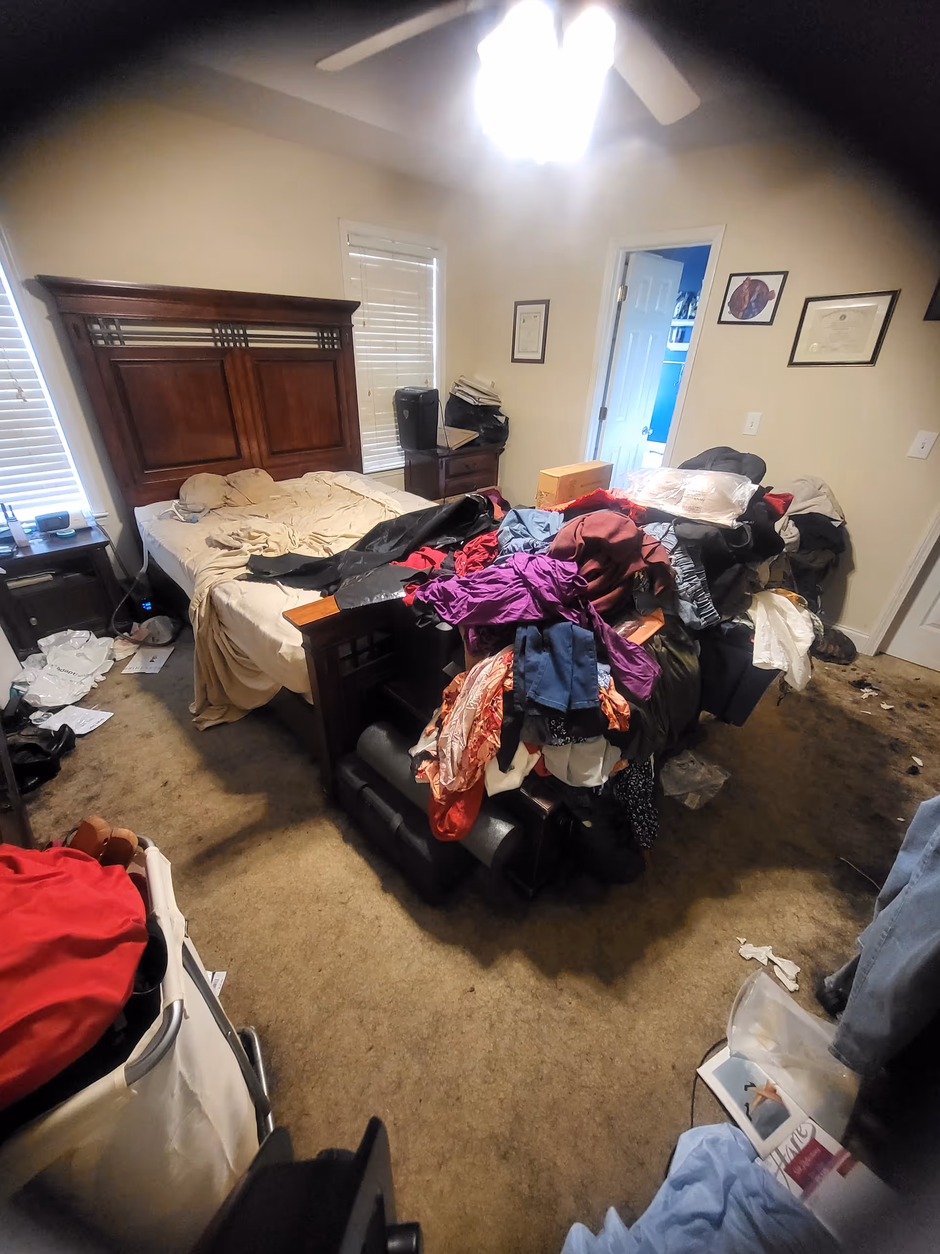 Messy bedroom with unmade bed, piled clothes, dresser, and scattered items.