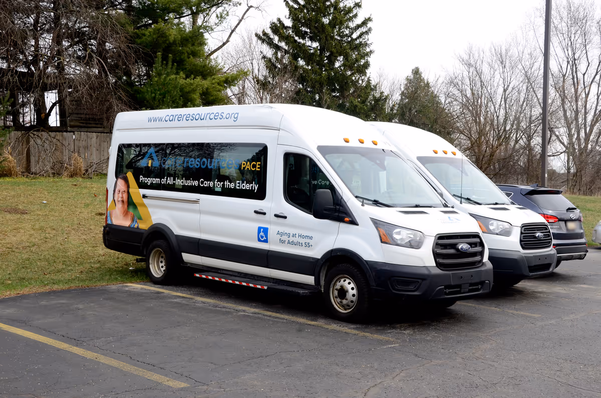 Two white vans labeled Care Resources – PACE parked in a lot.
