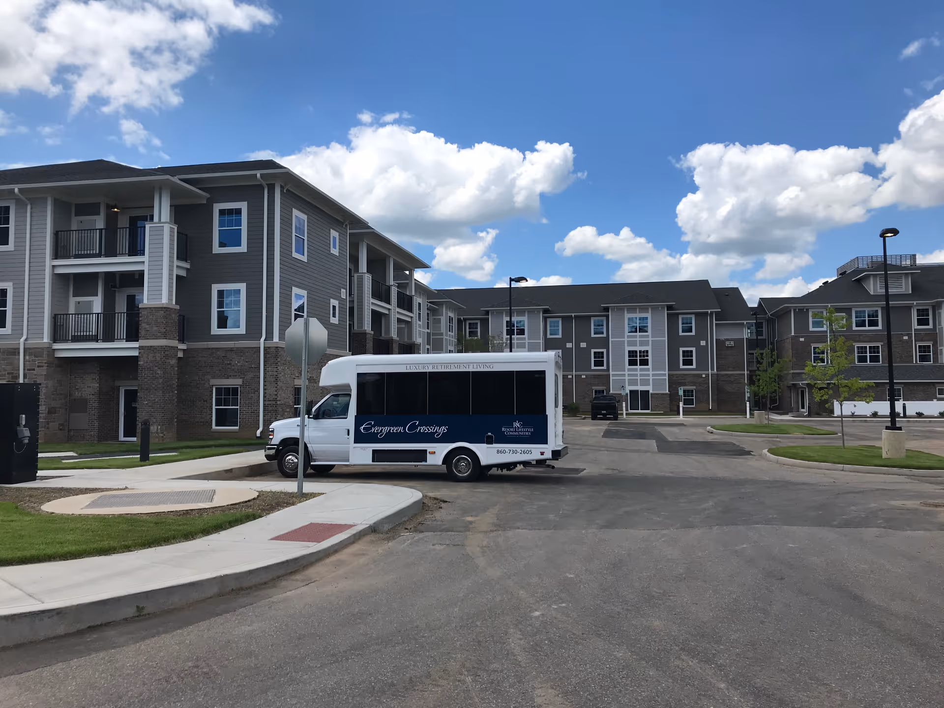 Evergreen Crossings retirement community exterior with a parked shuttle bus under blue sky