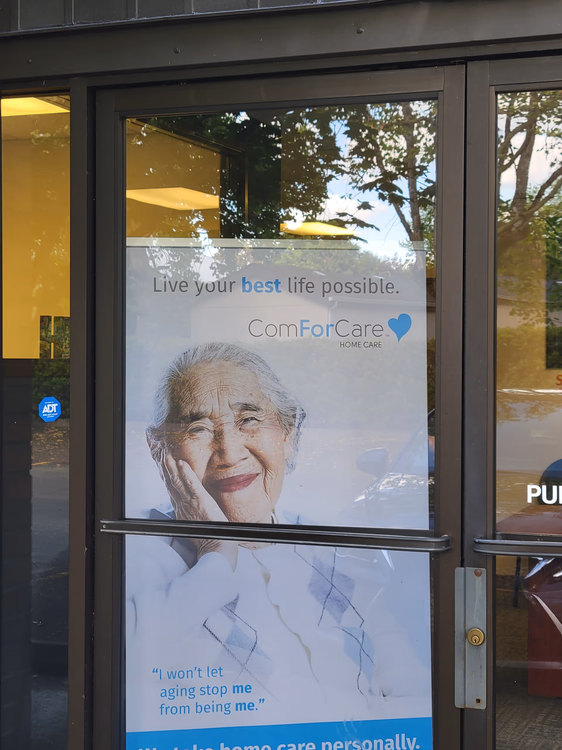 Glass entrance door with a poster of an elderly woman for ComForCare Home Care.