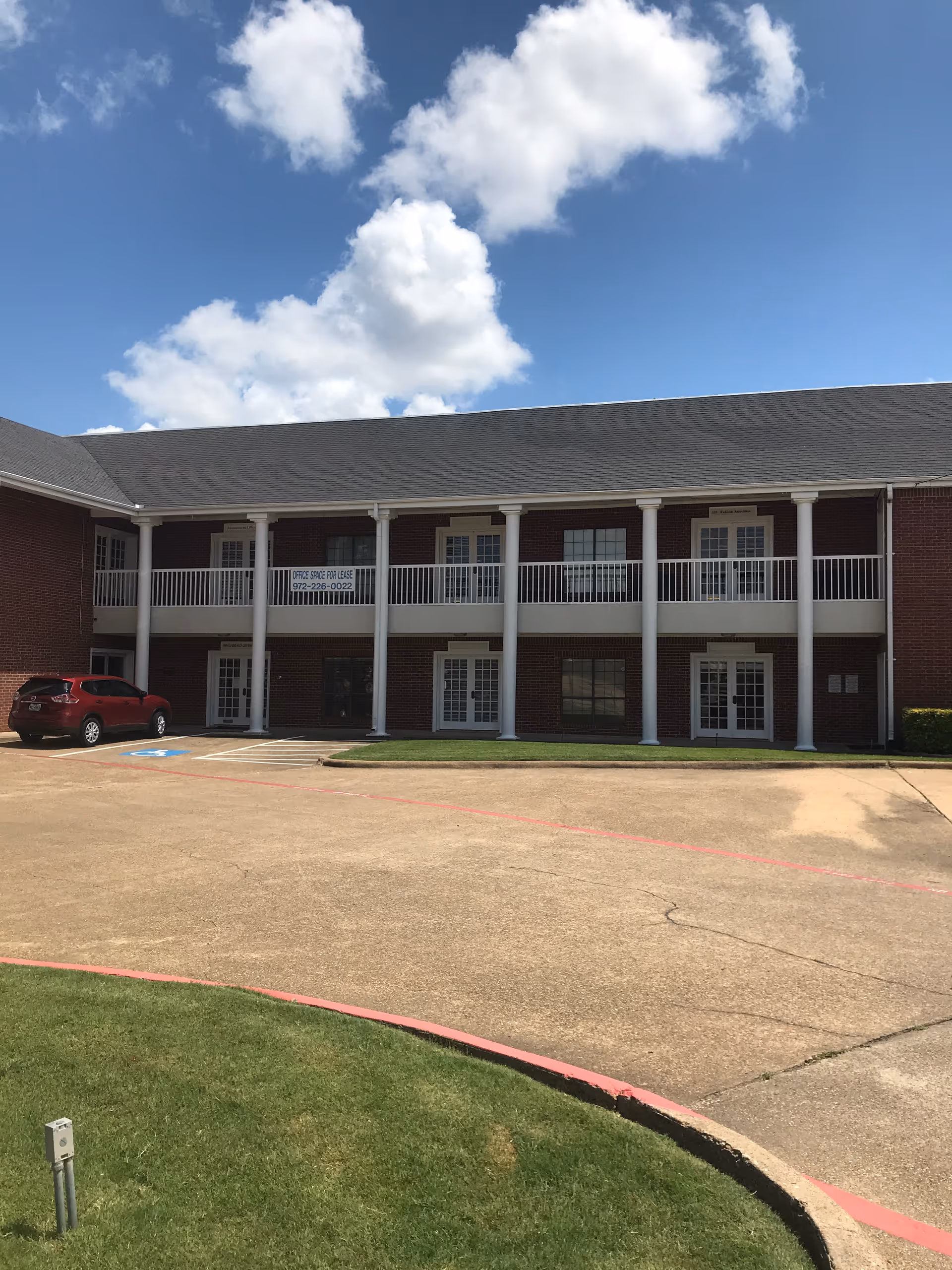 Brick two-story facility with white columns, balconies, and a parking lot.