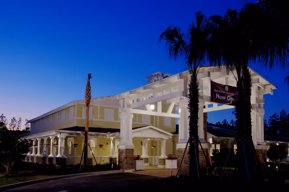 Exterior view of Serenades at West Orange with a lit entrance arch at dusk.