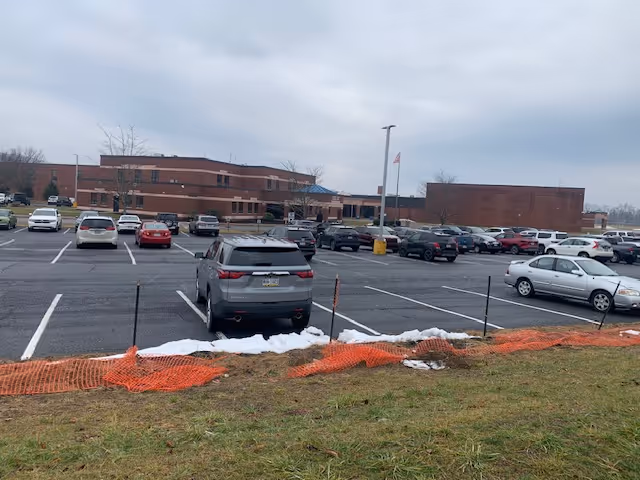 Exterior view of a brick senior living facility with cars in a parking lot.