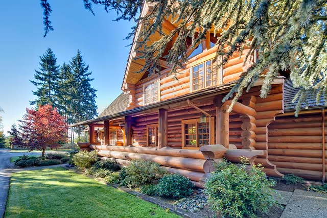 Log cabin-style senior living facility exterior with a covered porch and landscaping.