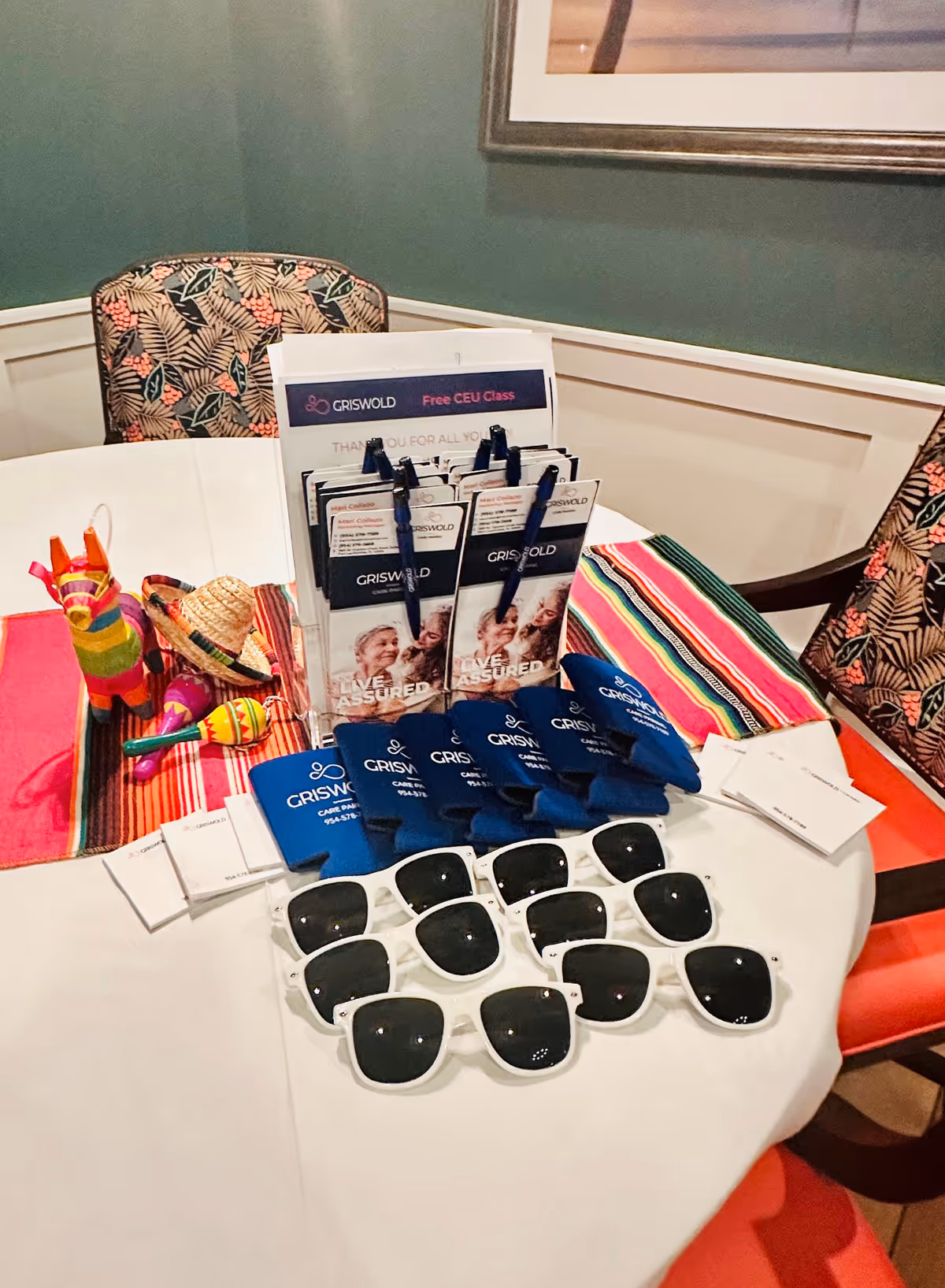 Round table displays Griswold brochures, sunglasses, and pens in a dining area.