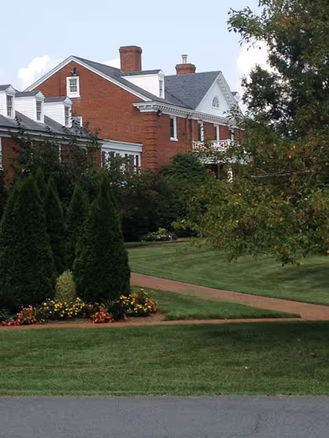 Brick senior living building with manicured lawn and path along the front