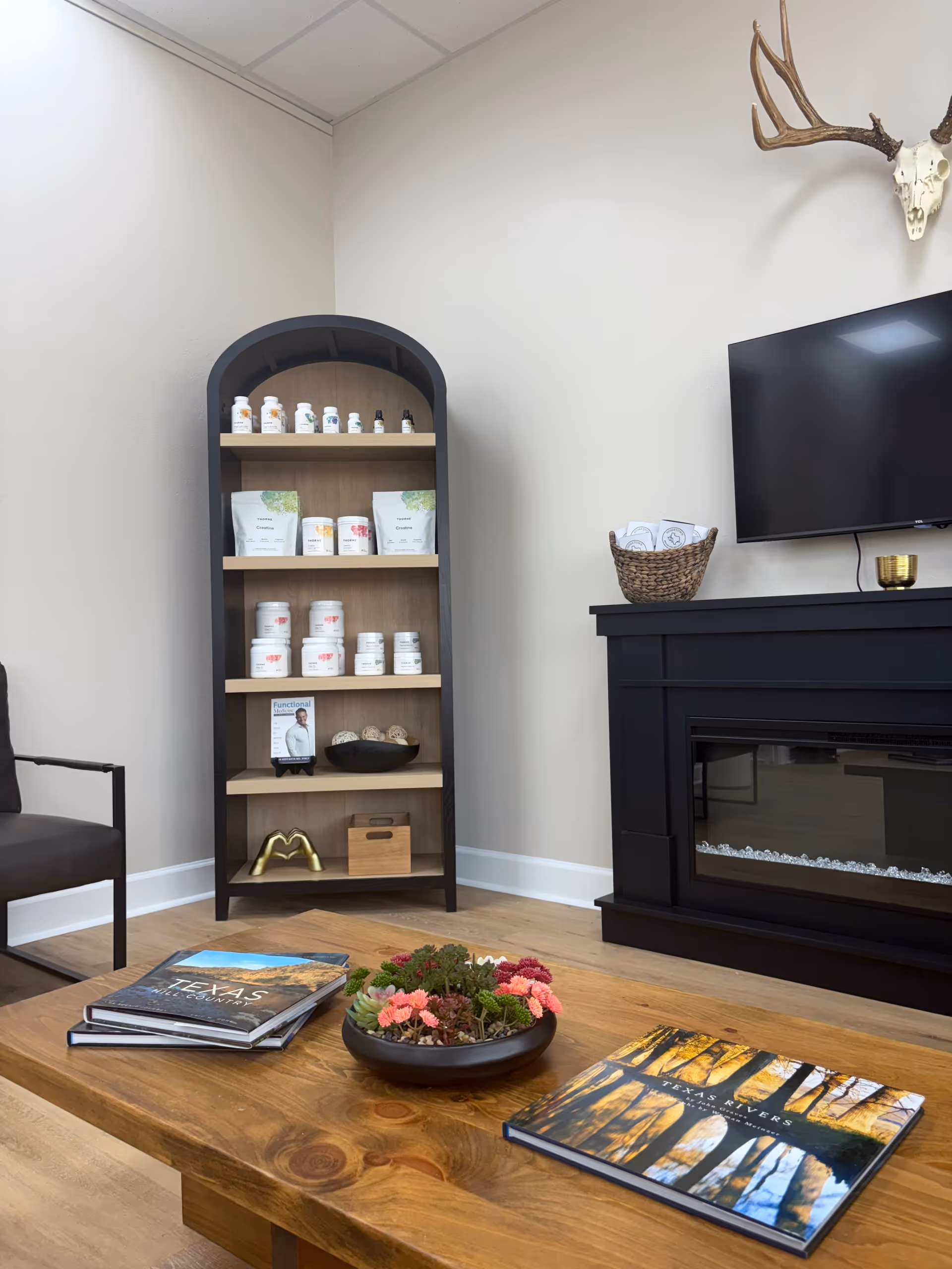 Cozy living room with a wood coffee table, magazines, shelving unit, and a fireplace.