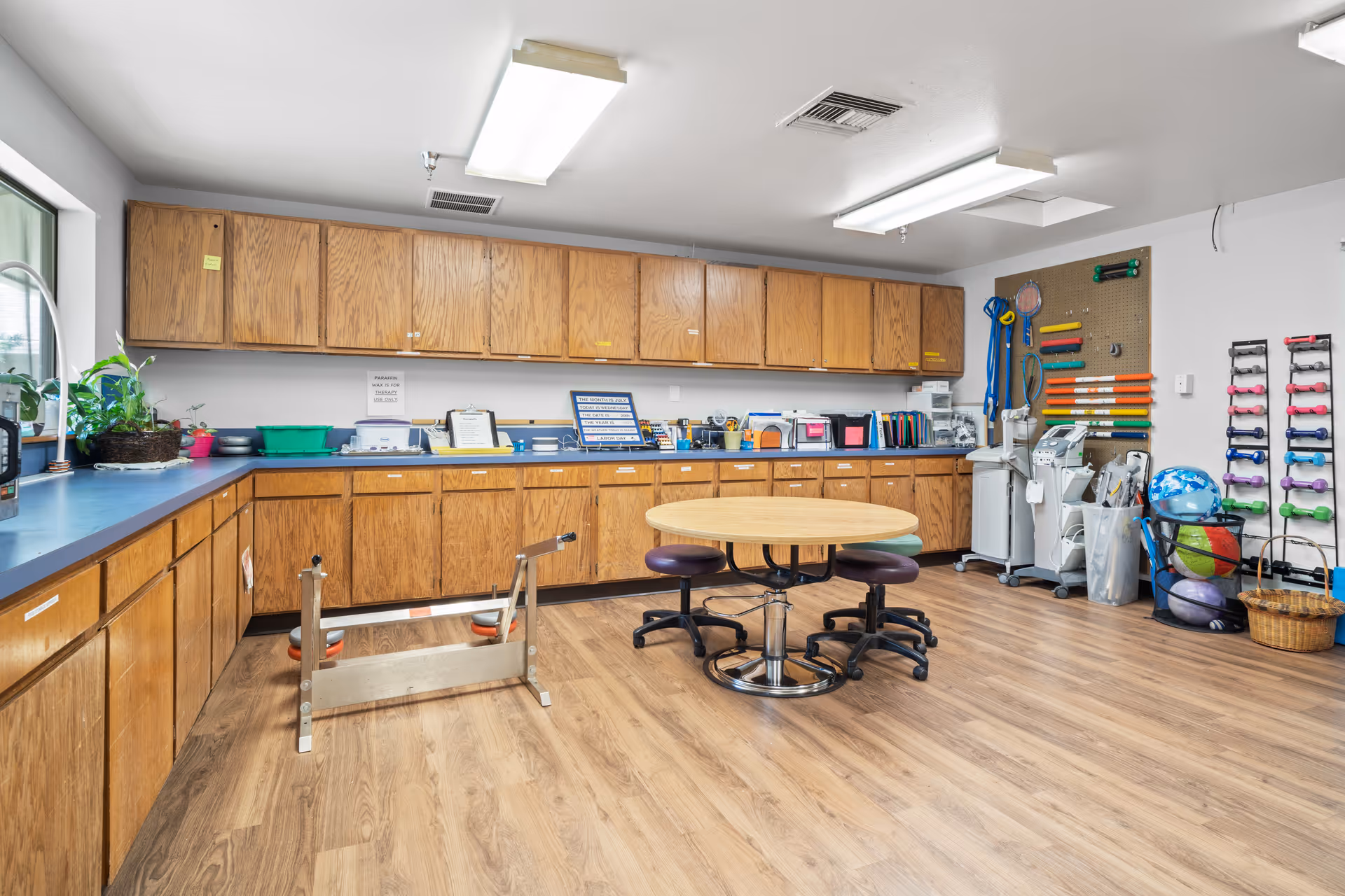 Well-lit interior room with wooden cabinets, a round table, and assorted exercise equipment.