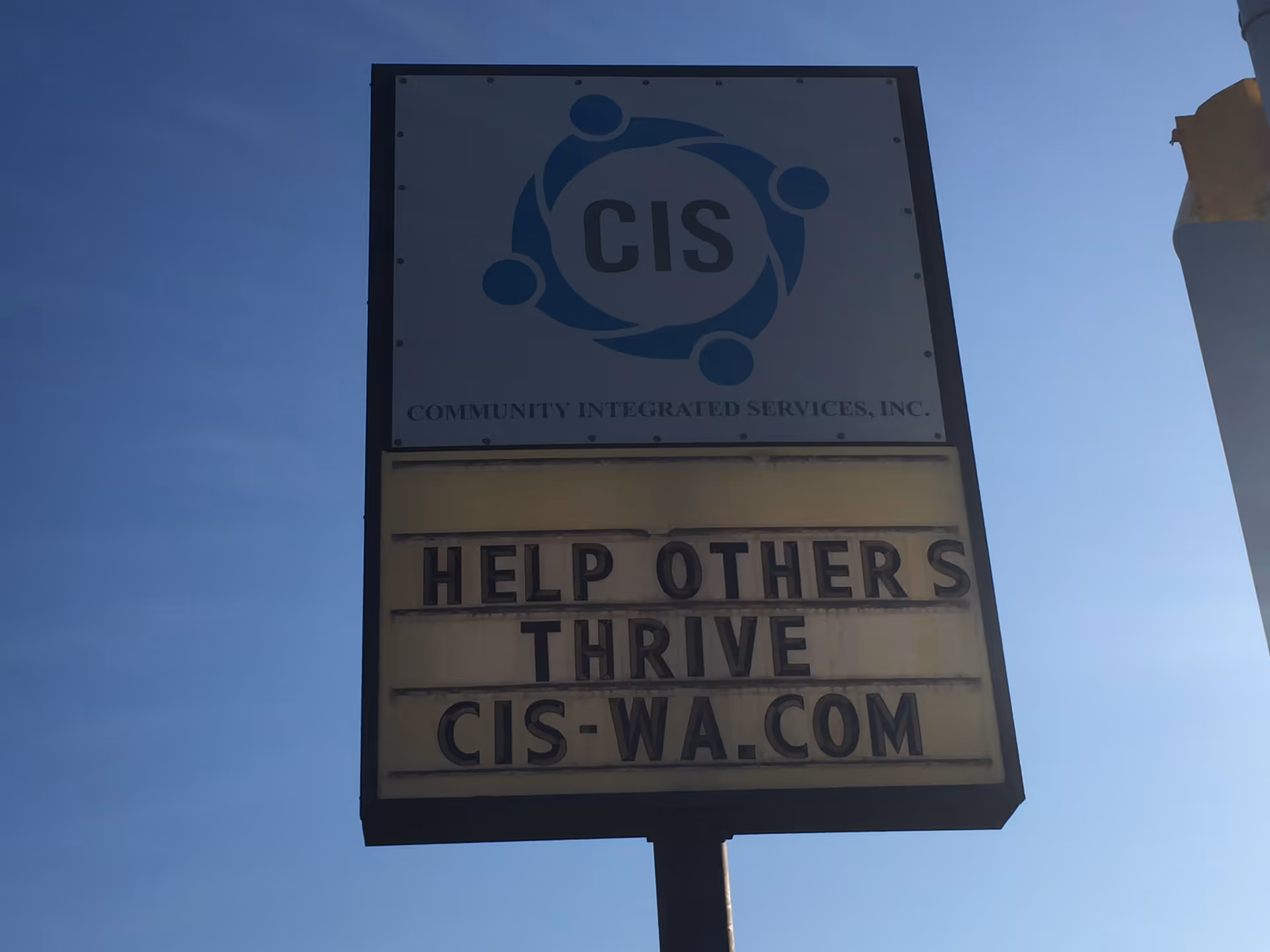 A tall sign displays the CIS logo and the slogan Help Others Thrive outdoors.