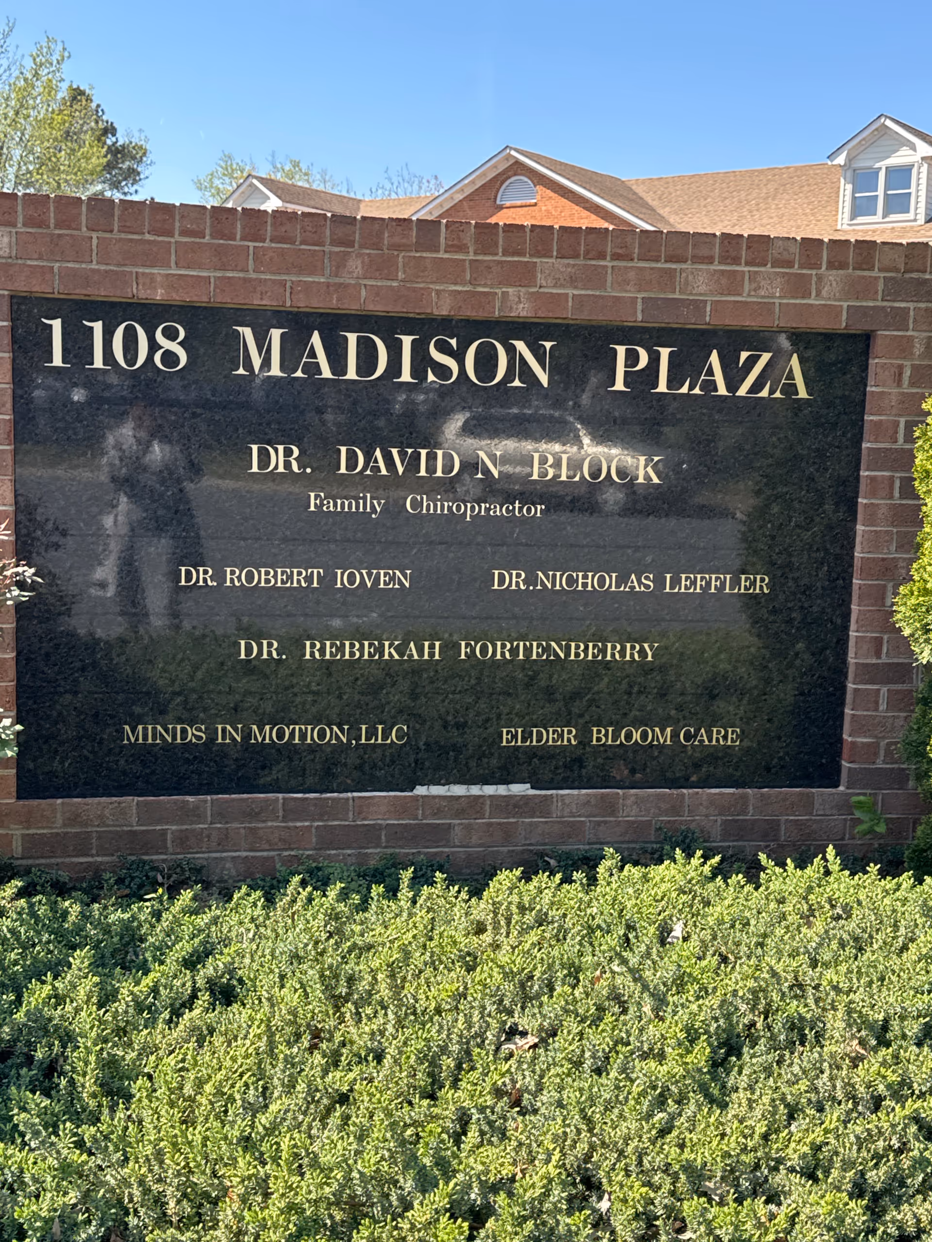 Large black plaque on a brick wall lists names and Elder Bloom Care.