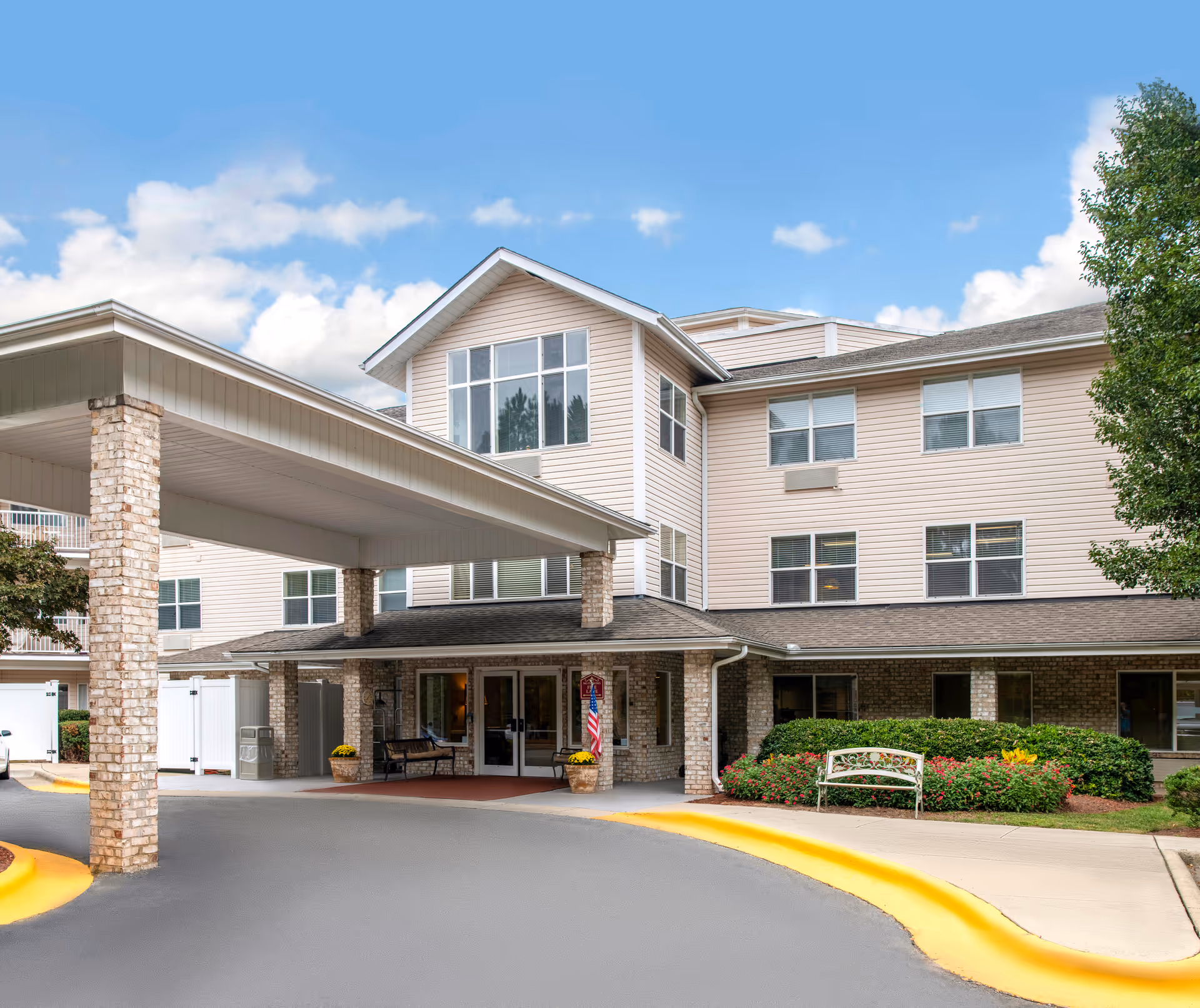 Senior living facility building with a covered entrance, stone columns, and landscaped front