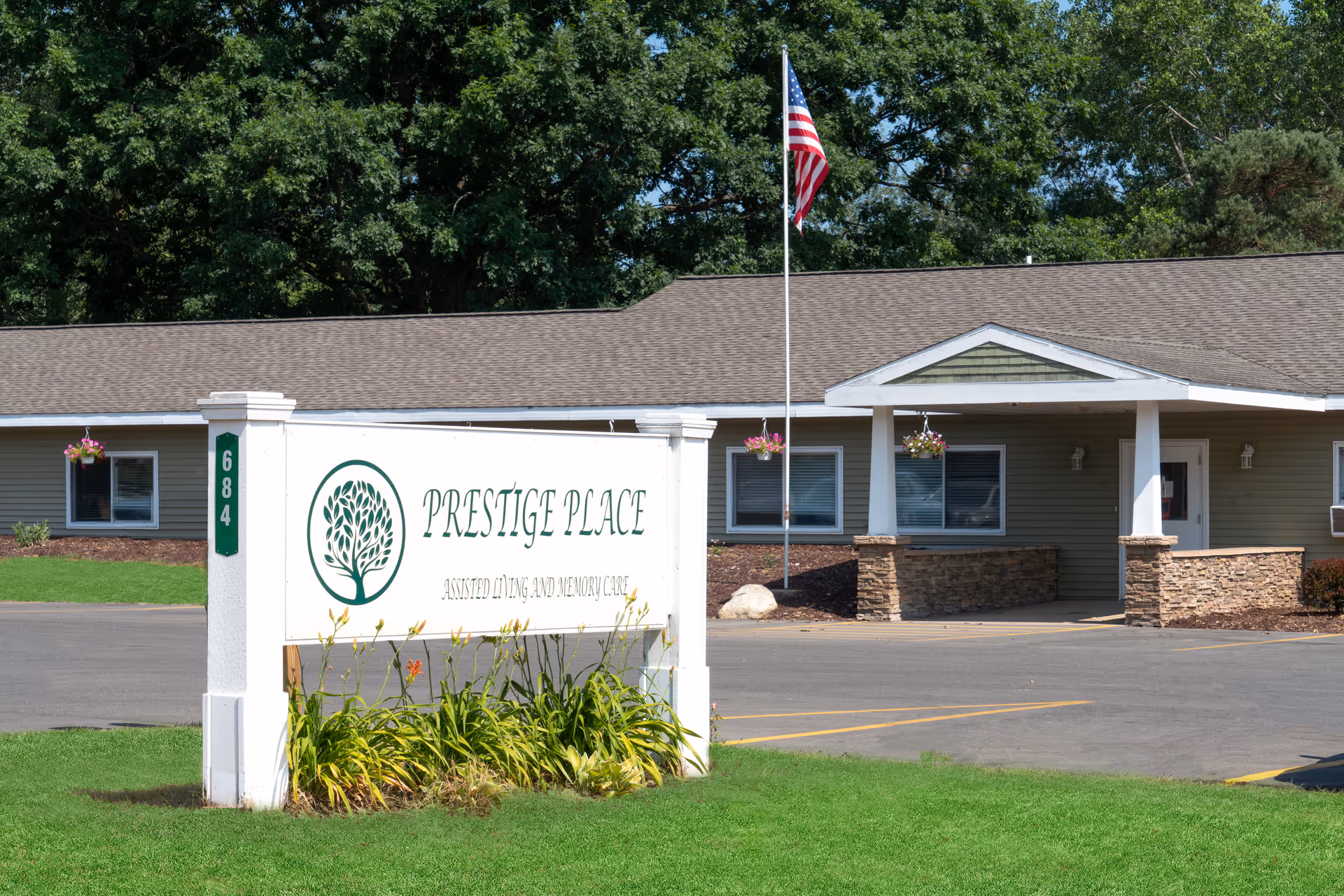 Front view of Americana Seniors facility with sign, American flag, and covered entrance.