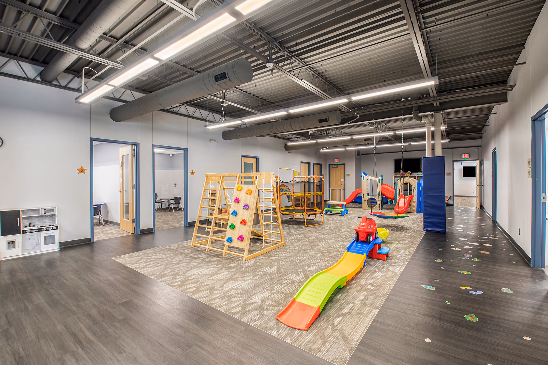 Indoor playroom featuring climbing wall, slides, and colorful activity equipment.