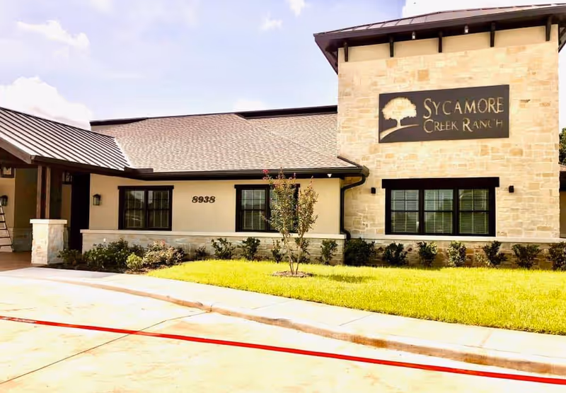 Exterior view of Sycamore Creek Ranch Memory Care building with sign and landscaped front.