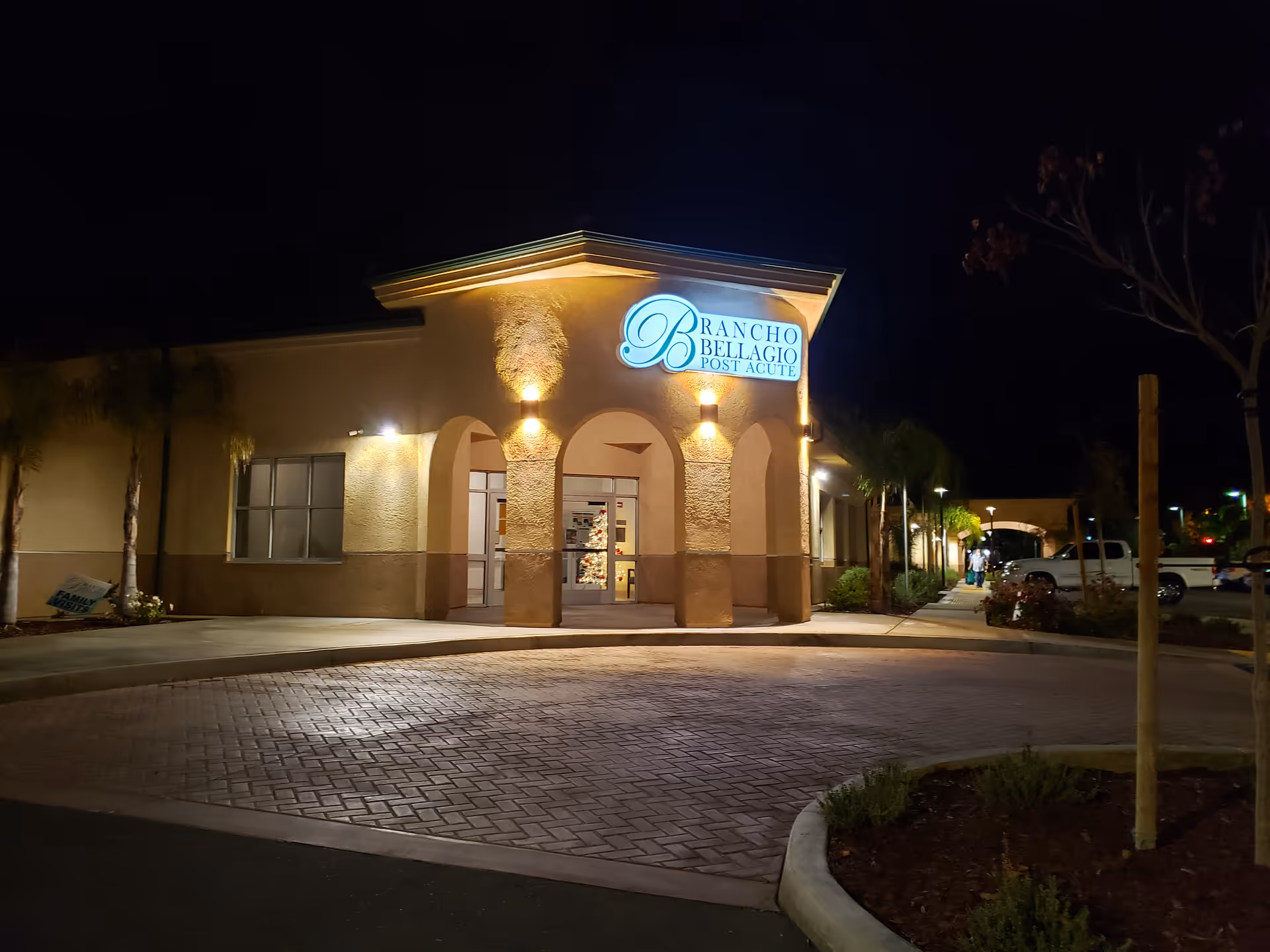 Nighttime exterior view of Rancho Bellagio Post Acute entrance with lit signage and arches.