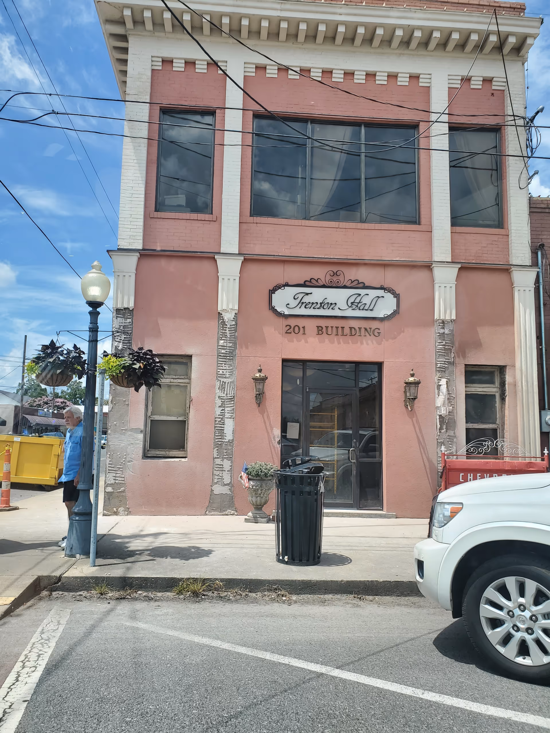 Two-story pink brick building with a storefront entrance and street scene.