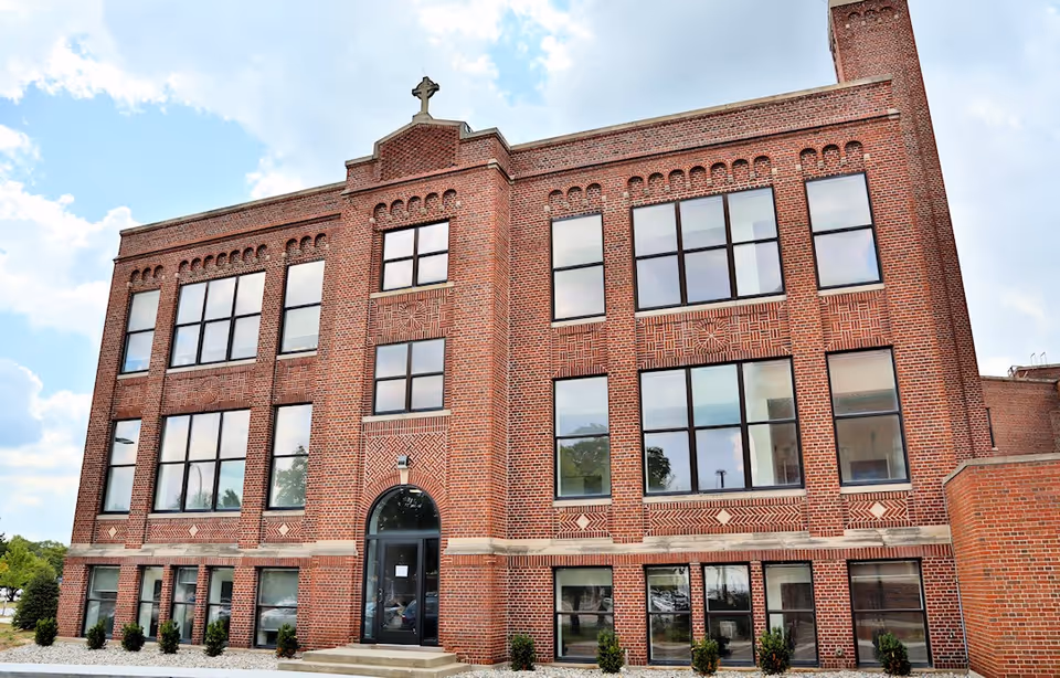 Three-story red brick building with large windows and a central arched entrance.