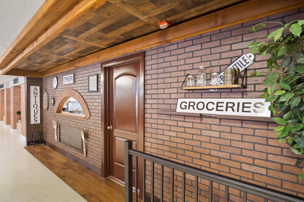 Brick-walled interior hallway with vintage shop signs reading Groceries, Antique, Diner.