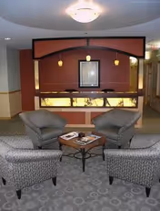 Senior living facility lobby with four armchairs around a coffee table and a reception desk.
