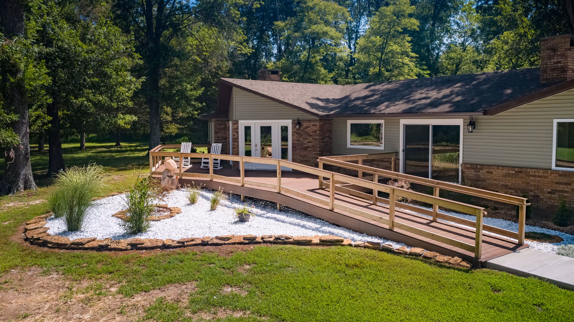 Front view of a single-story senior living facility with a wooden ramp and landscaped yard.