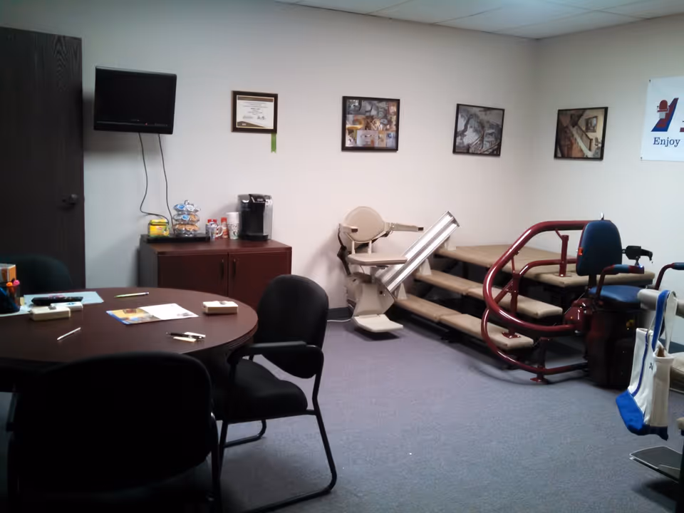 A small interior room with a stair lift, round table, and wall pictures.