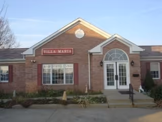 Brick building front with Villa Maria sign and glass entrance door.