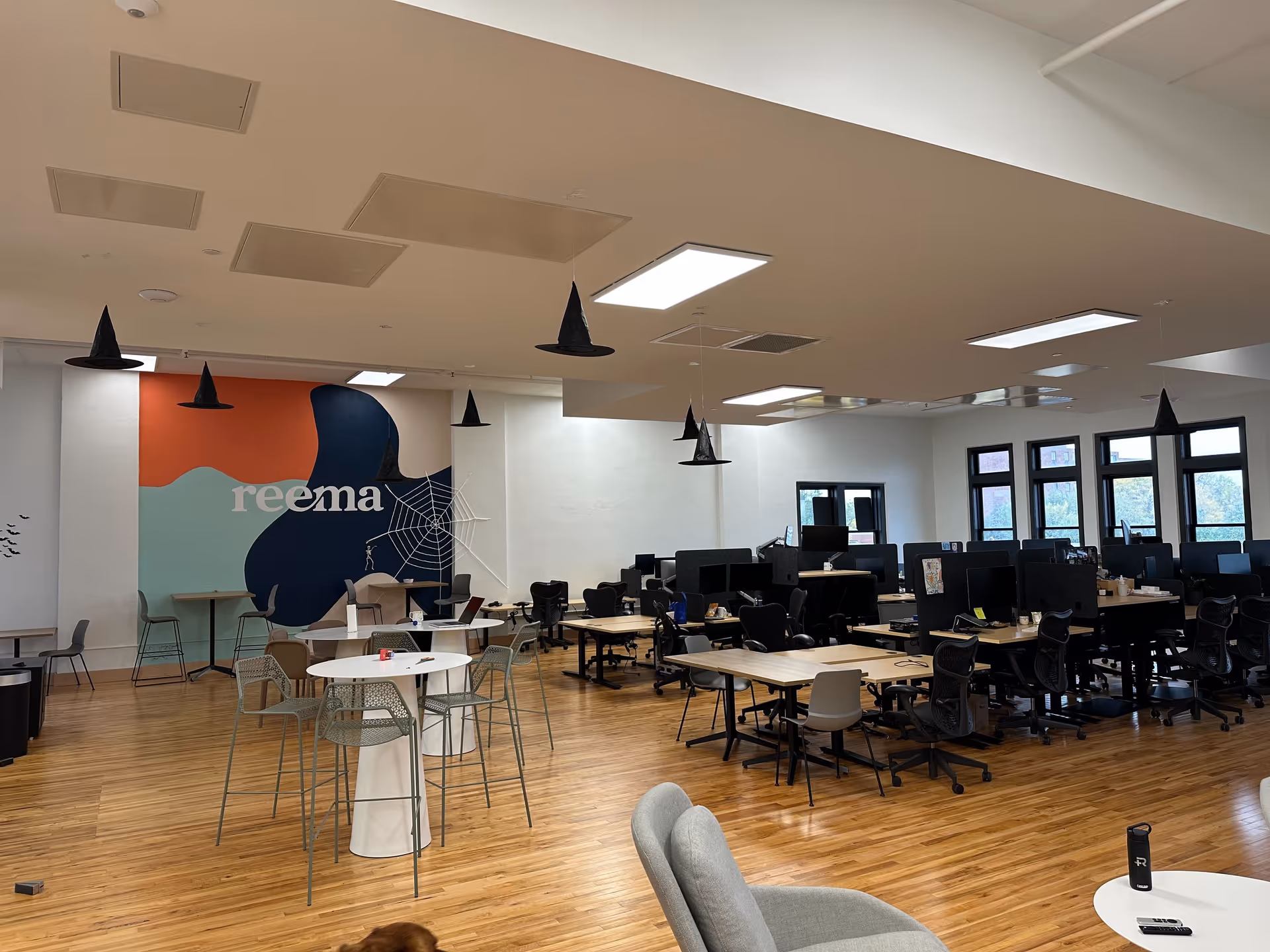 Open interior workspace with desks, computers, and a colorful Reema mural on the wall.