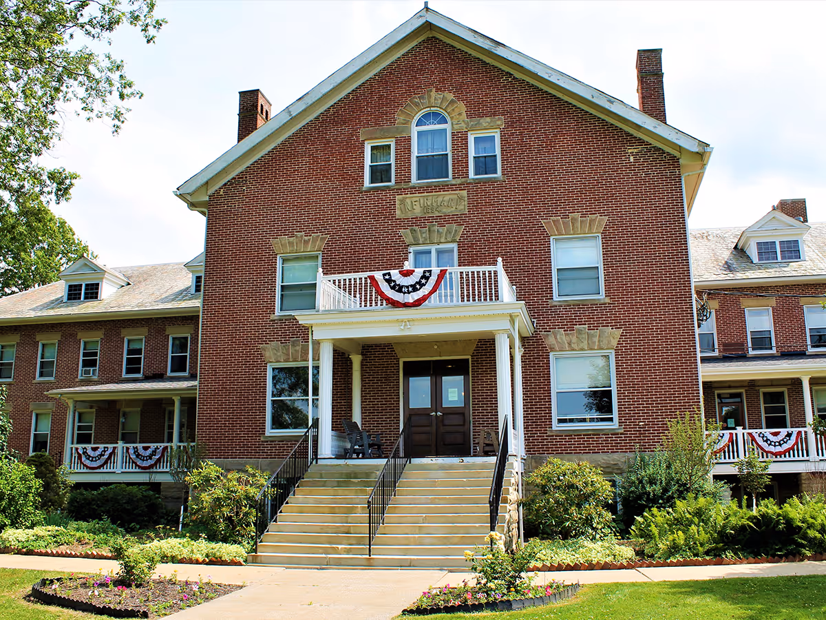 Brick senior living facility with steps, front entrance, and patriotic bunting.