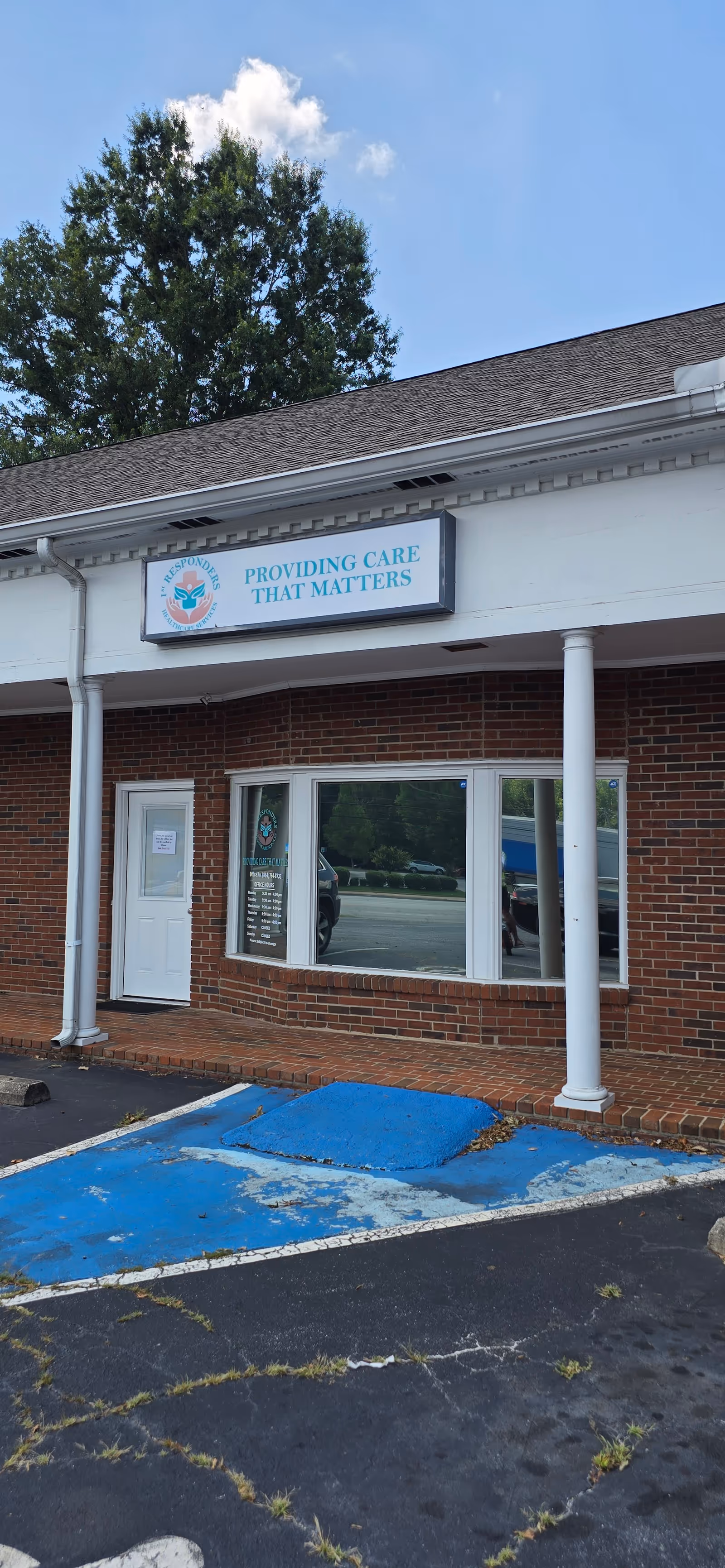 Brick facility exterior with sign 'Providing care that matters' and blue parking area.