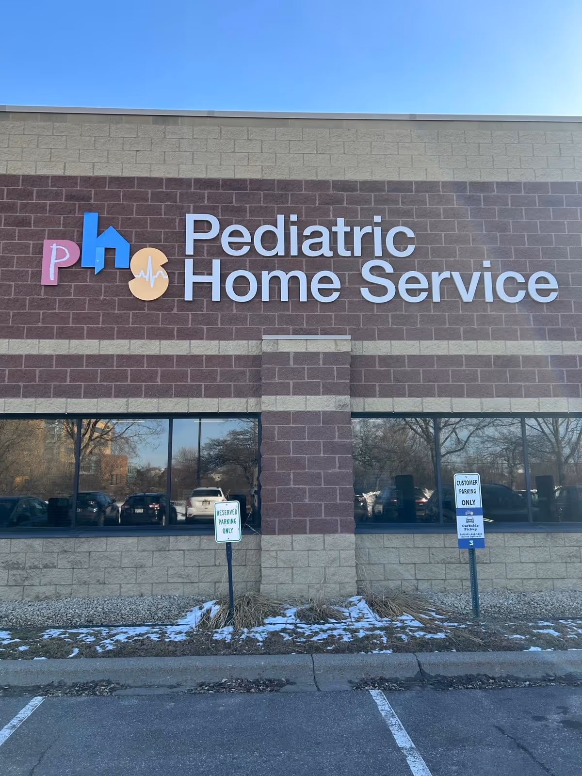 Exterior view of a brick building with large Pediatric Home Service sign and parking lot.