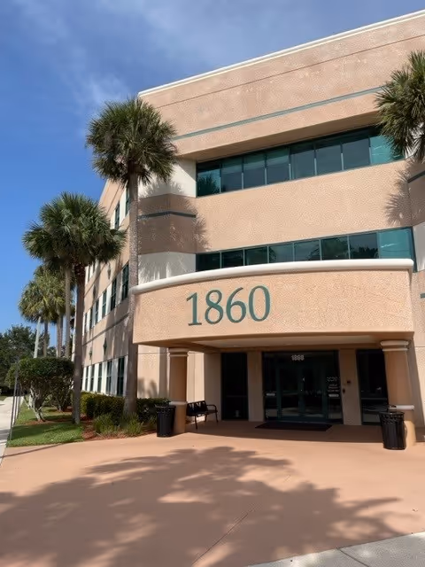 A two-story peach-colored building with palm trees sits beside an entrance marked 1860.