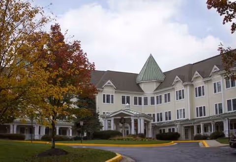 Sunrise of Pikesville residential senior living building with a circular driveway and autumn trees.
