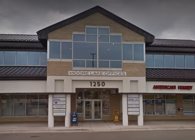 Front view of a two-story office building with large glass windows and Moore Lake Offices sign.