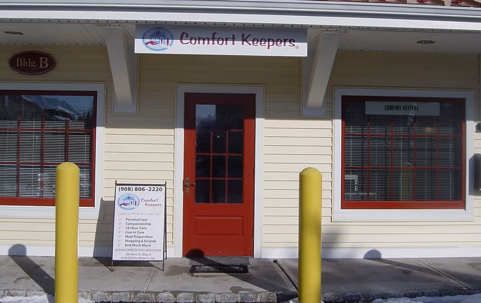 Front of Comfort Keepers facility with red door, windows, and sidewalk sign